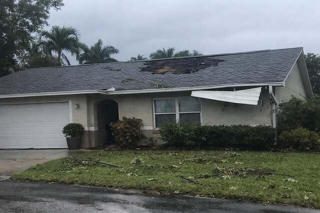 A shingle roof with sections torn away by a storm