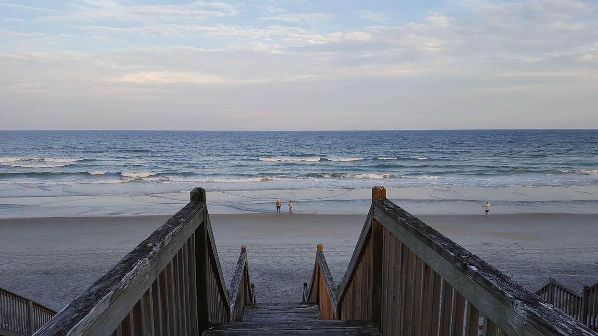 A sandy path through sea oats toward the ocean